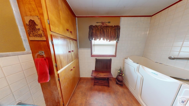 bathroom featuring crown molding, a bathing tub, washer and clothes dryer, and tile walls