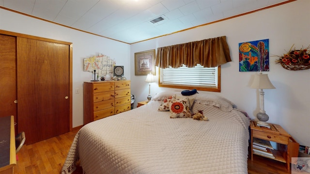 bedroom with hardwood / wood-style flooring, a closet, and crown molding