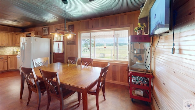 dining area with wooden ceiling and wood walls