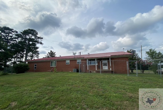 back of property with a lawn and central AC