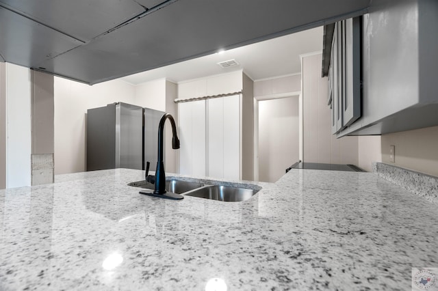 kitchen featuring light stone countertops, crown molding, range, and sink