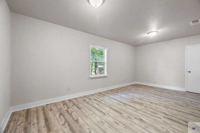 spare room featuring a textured ceiling and light wood-type flooring