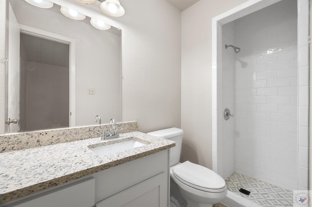 bathroom featuring a tile shower, toilet, and vanity