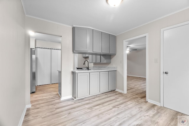 kitchen featuring crown molding, gray cabinets, and light hardwood / wood-style flooring