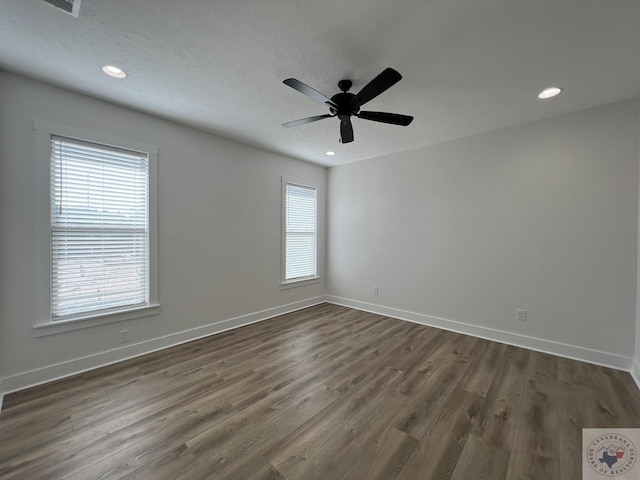 unfurnished room featuring a healthy amount of sunlight, dark wood-type flooring, and ceiling fan