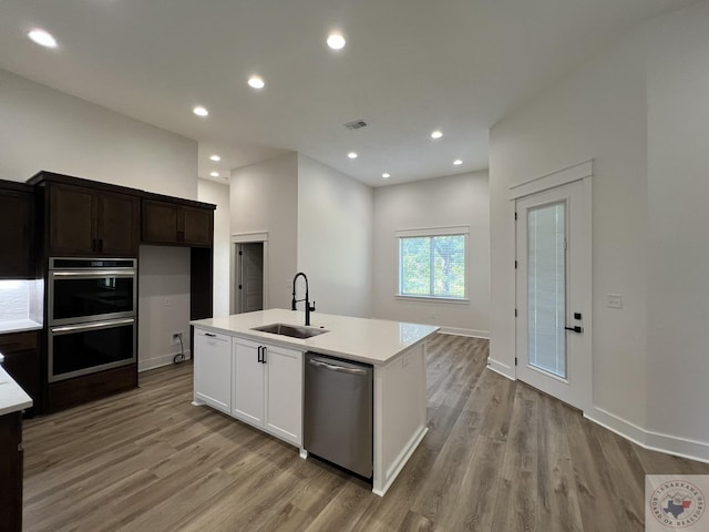 kitchen featuring white cabinets, appliances with stainless steel finishes, light hardwood / wood-style floors, sink, and a center island with sink