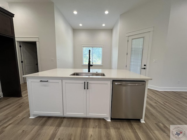 kitchen featuring dishwasher, sink, light wood-type flooring, white cabinetry, and a kitchen island with sink