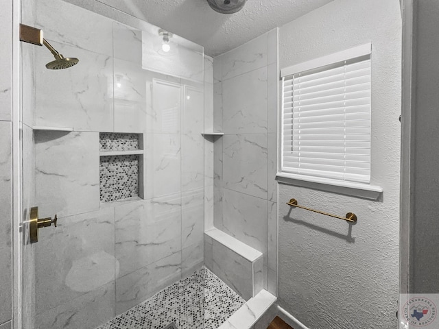 bathroom with a tile shower and a textured ceiling