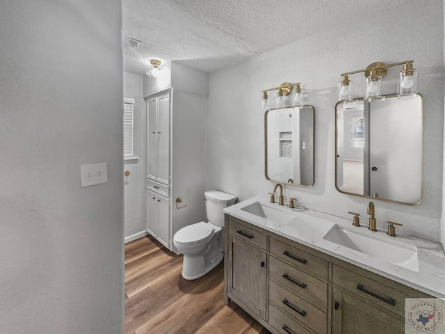 bathroom featuring vanity, hardwood / wood-style flooring, a textured ceiling, and toilet