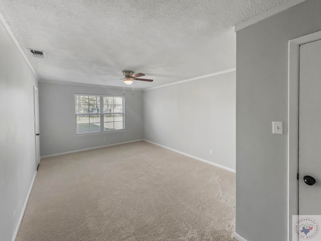 carpeted spare room featuring ceiling fan, ornamental molding, and a textured ceiling