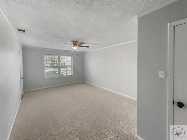 carpeted spare room featuring ceiling fan, ornamental molding, and a textured ceiling