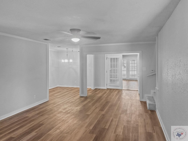 unfurnished living room featuring ceiling fan with notable chandelier, crown molding, a textured ceiling, and wood-type flooring