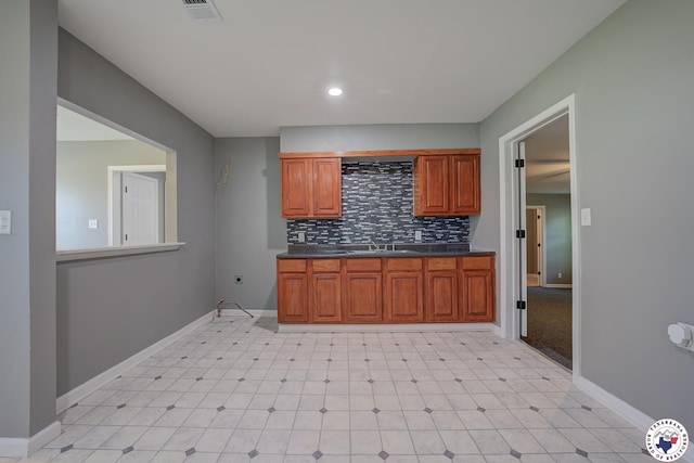 1107 Wheeler St, Texarkana, TX 75501 - kitchen with dark countertops, tasteful backsplash, baseboards, light flooring, and brown cabinets