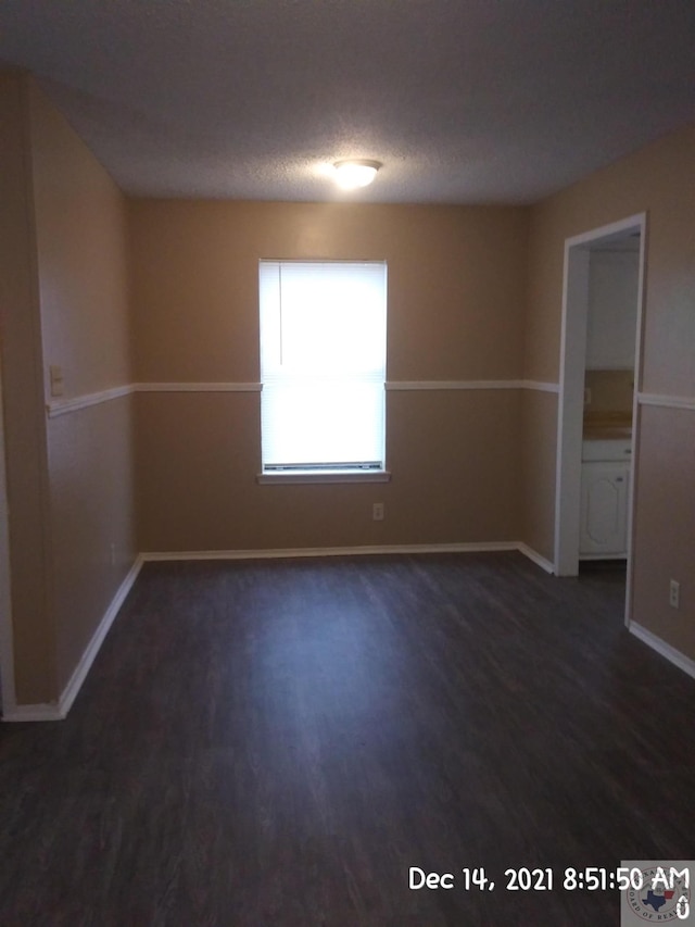 spare room with a textured ceiling and dark hardwood / wood-style flooring