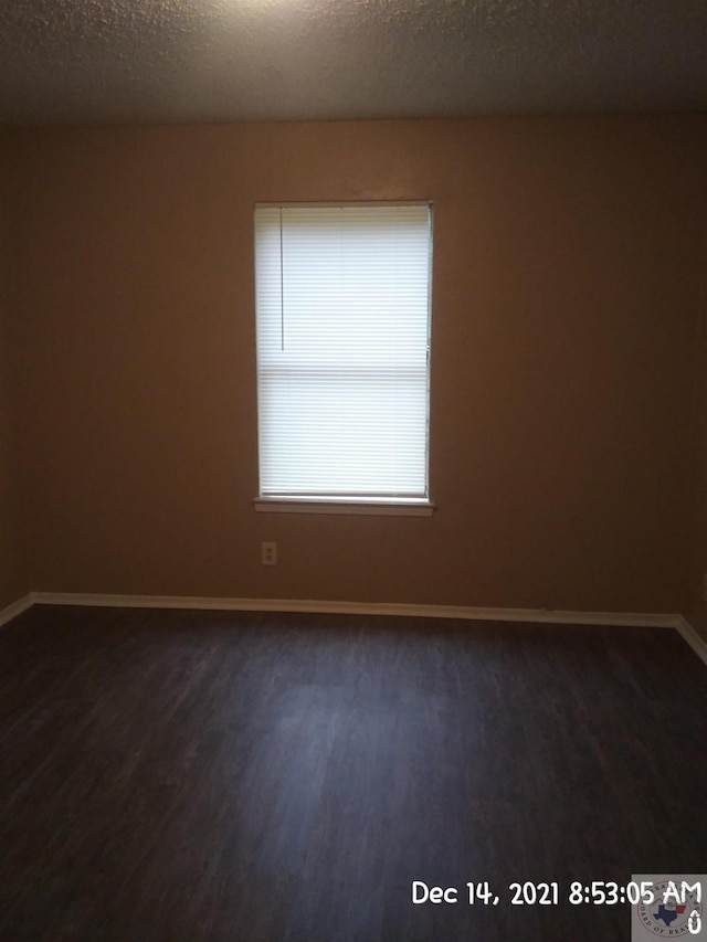 unfurnished room featuring a textured ceiling and dark hardwood / wood-style floors