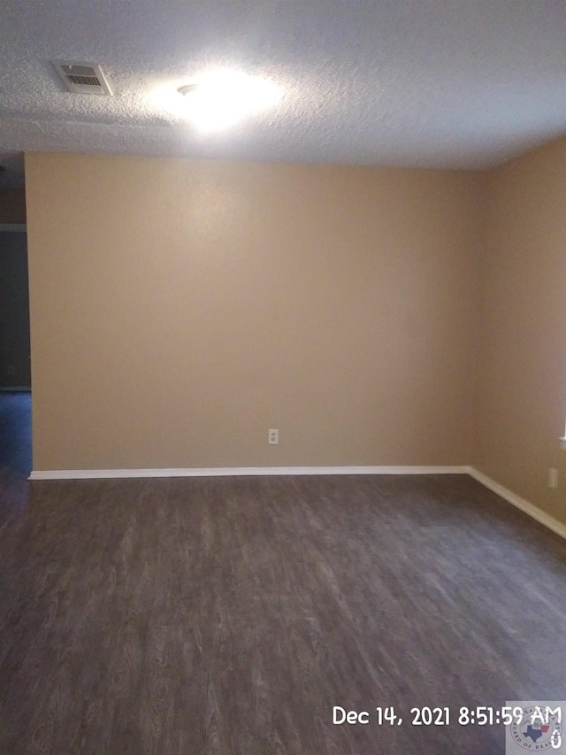 spare room featuring a textured ceiling and dark hardwood / wood-style floors