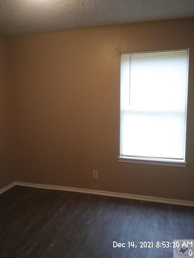 empty room with dark hardwood / wood-style floors and a textured ceiling