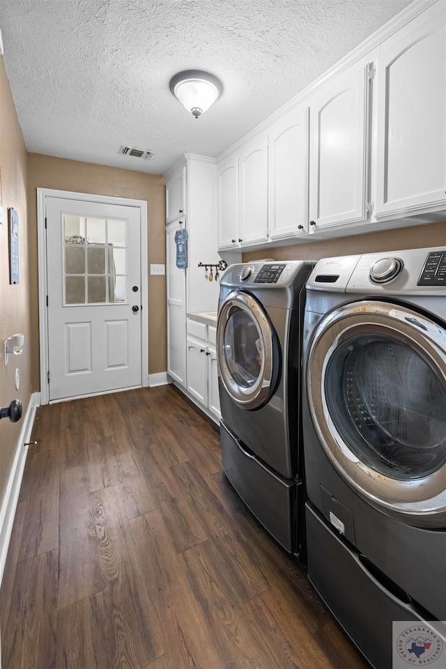 laundry room featuring dark wood-type flooring, cabinets, and washer and clothes dryer