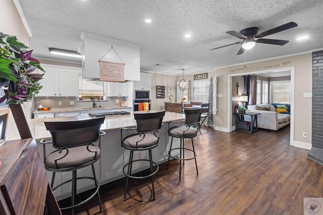 kitchen featuring a kitchen bar, white cabinets, hanging light fixtures, and appliances with stainless steel finishes