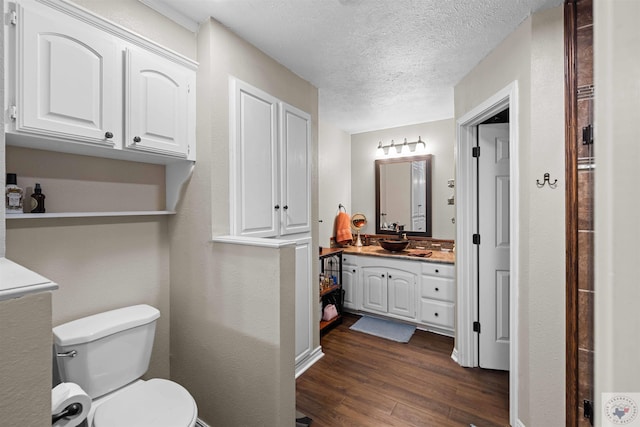 bathroom featuring hardwood / wood-style flooring, a textured ceiling, toilet, and vanity