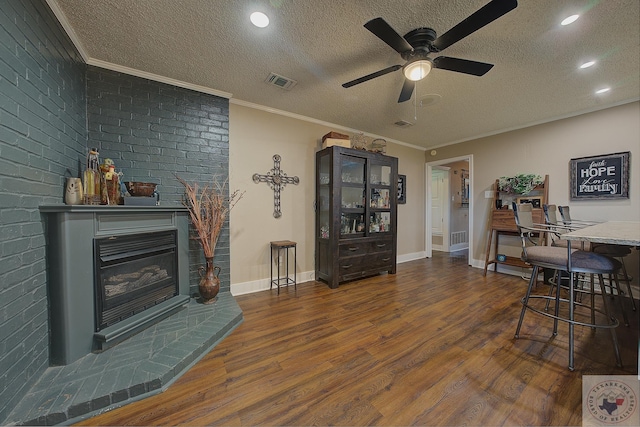 living room featuring ceiling fan, dark wood-type flooring, a textured ceiling, and ornamental molding