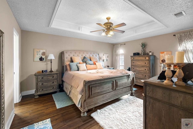 bedroom featuring ceiling fan, a raised ceiling, dark wood-type flooring, and a textured ceiling