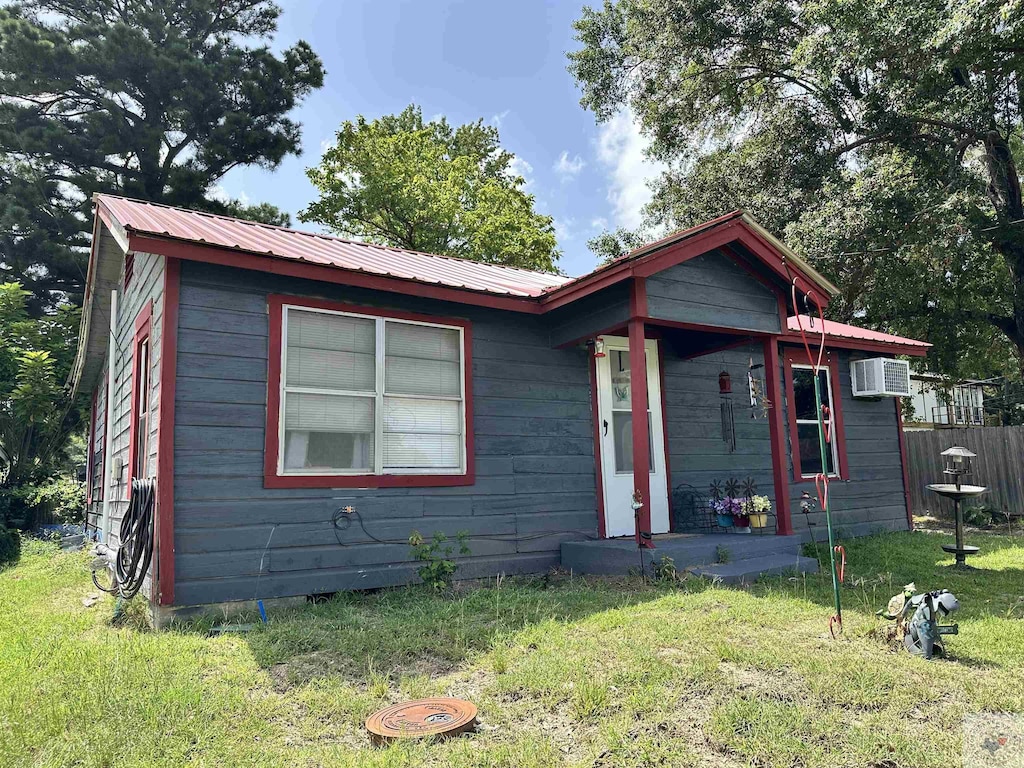 view of front of property featuring a front yard and a wall mounted AC