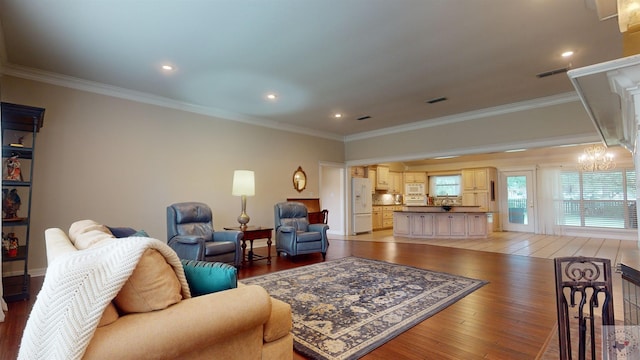 living room featuring hardwood / wood-style flooring, ornamental molding, and a notable chandelier