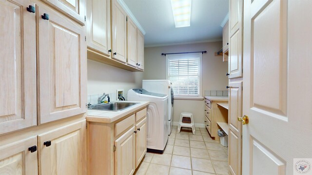 laundry area featuring crown molding, independent washer and dryer, sink, cabinets, and light tile patterned flooring