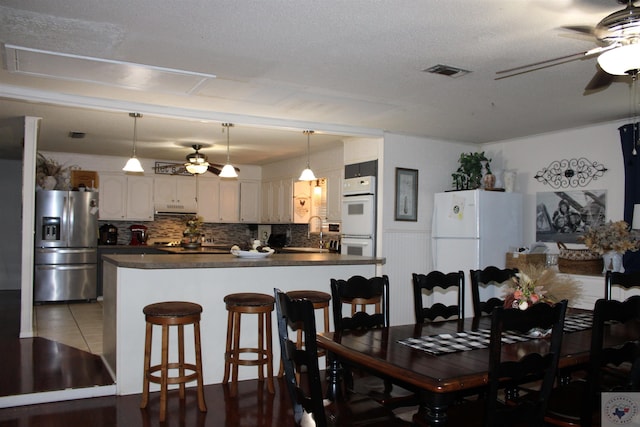 tiled dining area featuring sink, ceiling fan, and a textured ceiling