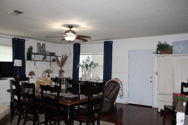 dining space featuring dark wood-type flooring, a textured ceiling, and ceiling fan