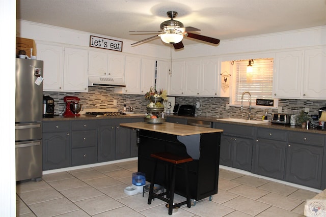 kitchen featuring ceiling fan, sink, white cabinetry, a center island, and stainless steel appliances