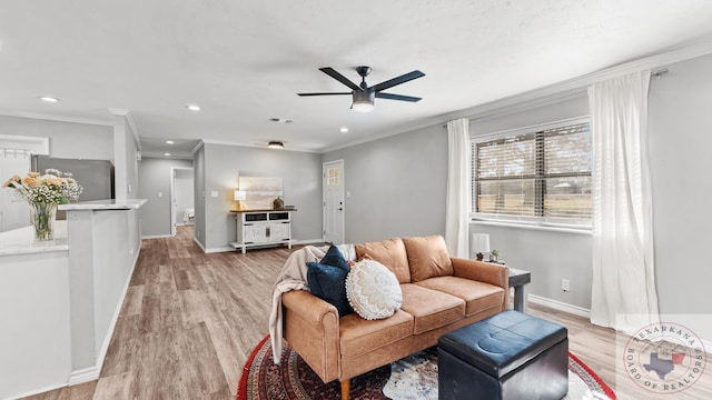 living room featuring ceiling fan, ornamental molding, and light wood-type flooring