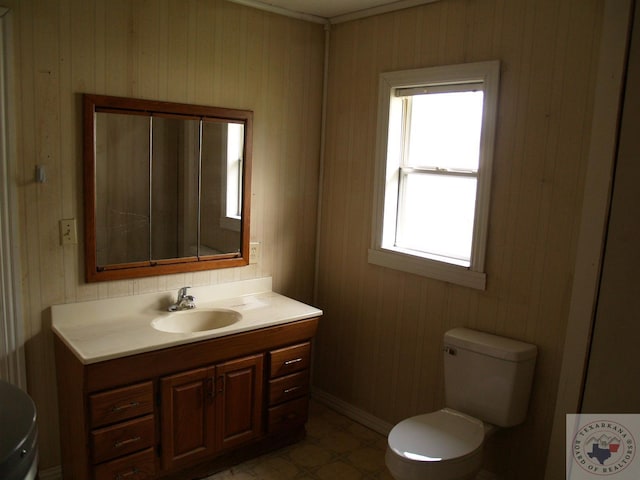 bathroom with vanity, toilet, and wood walls