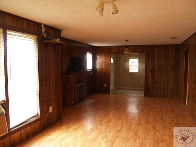 empty room with a wealth of natural light, wooden walls, and a fireplace