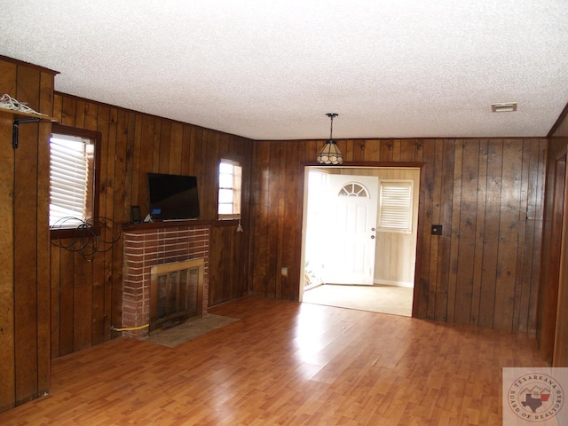 unfurnished living room featuring wood walls, a healthy amount of sunlight, and a textured ceiling