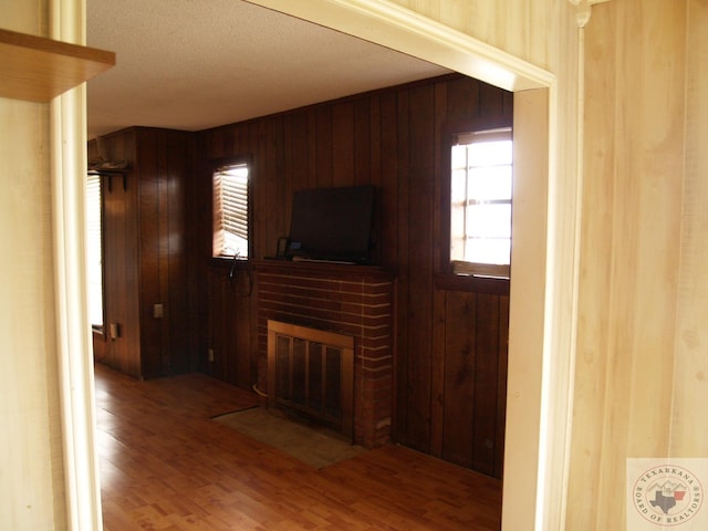 living room featuring wood walls, hardwood / wood-style floors, and a brick fireplace