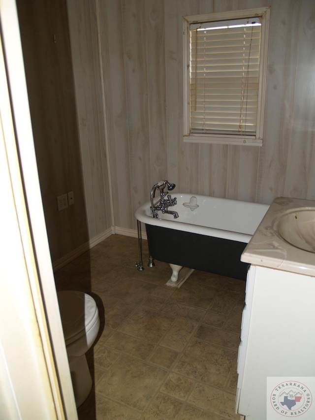 bathroom with vanity, toilet, and a washtub