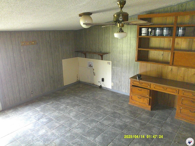 laundry room with ceiling fan, baseboards, wooden walls, and dark tile patterned flooring