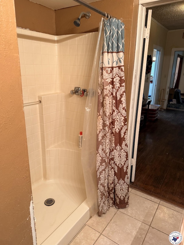 full bath with tile patterned floors, ornamental molding, a stall shower, and a textured ceiling