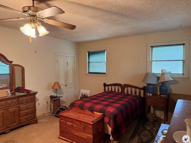 bedroom with light colored carpet, a closet, ceiling fan, and a textured ceiling
