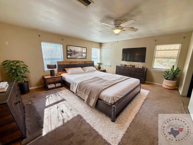 carpeted bedroom featuring multiple windows and ceiling fan