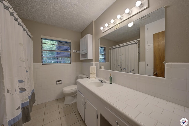814 Hawkins Ave, Wake Village, TX 75501 - bathroom featuring tile patterned floors, vanity, toilet, tile walls, and wainscoting