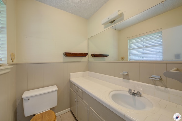 814 Hawkins Ave, Wake Village, TX 75501 - bathroom with a textured ceiling, vanity, toilet, a wainscoted wall, and tile patterned floors