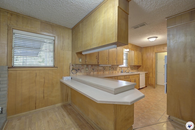814 Hawkins Ave, Wake Village, TX 75501 - kitchen featuring dishwasher, a textured ceiling, a sink, light countertops, and wood walls