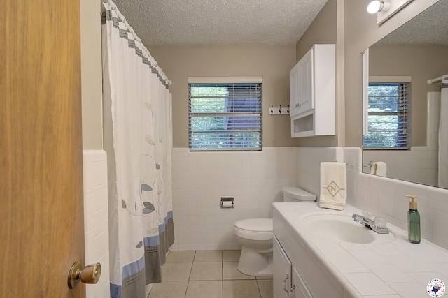 814 Hawkins Ave, Wake Village, TX 75501 - bathroom featuring tile patterned flooring, tile walls, toilet, vanity, and a textured ceiling