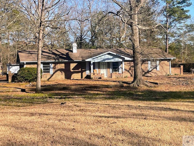 view of front facade with a front yard, a chimney, and brick siding