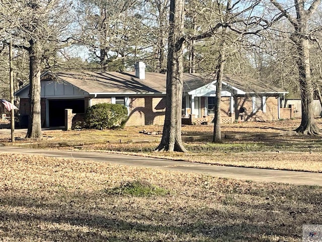 bungalow-style home featuring brick siding, a chimney, and board and batten siding