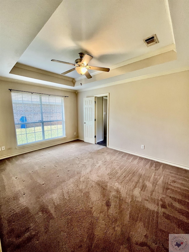 unfurnished room featuring ornamental molding, carpet floors, ceiling fan, and a raised ceiling