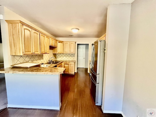 kitchen featuring tasteful backsplash, stainless steel refrigerator, kitchen peninsula, dark hardwood / wood-style flooring, and light brown cabinets